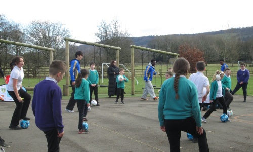 Children on playground with Leeds United players and footballs